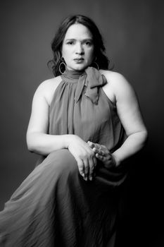 A sophisticated black and white portrait of a woman sitting gracefully in a studio setting.