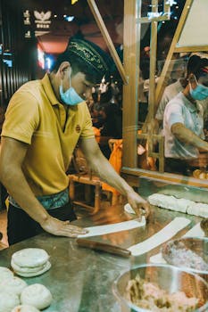 A vendor preparing dough at a vibrant night market food stall.
