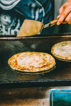 Close-up of a street vendor cooking traditional flatbreads on a griddle.