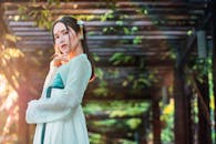 一位美丽的女子在阳光明媚的凉棚下，优雅地展示着中国传统服饰