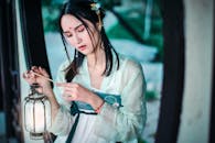 一位身着传统服装的亚洲女子优雅地拿着装饰灯笼，显得宁静而内省