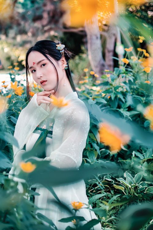 Free Portrait of an Asian woman surrounded by vibrant flowers in a garden. Stock Photo