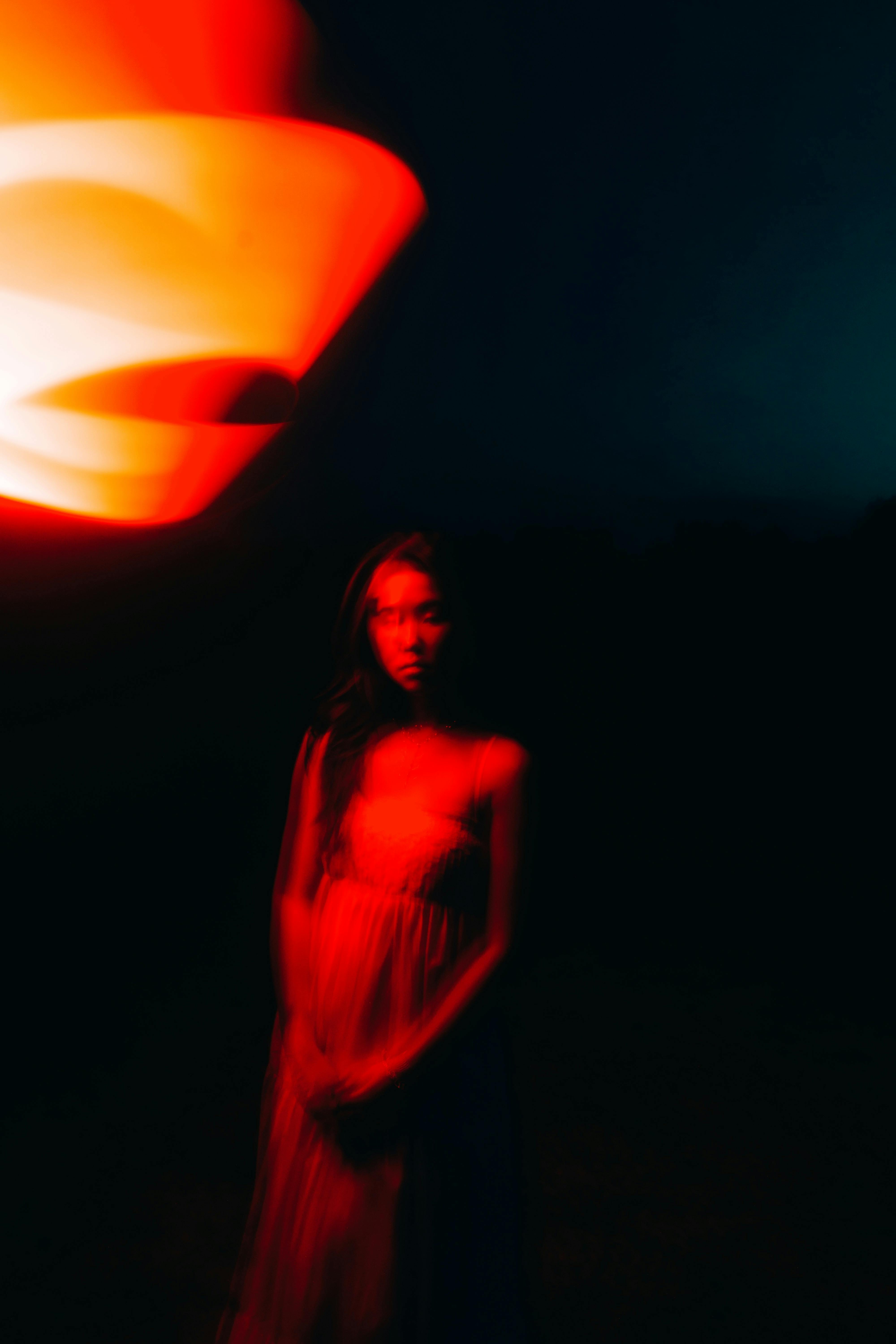 Dramatic portrait of a woman with abstract red lighting effect at night, creating an ethereal and moody atmosphere.