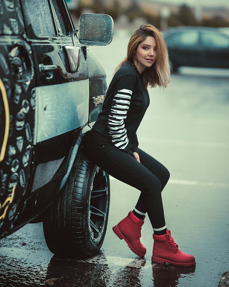 Woman Sitting On Parked Vehicle Front Tire