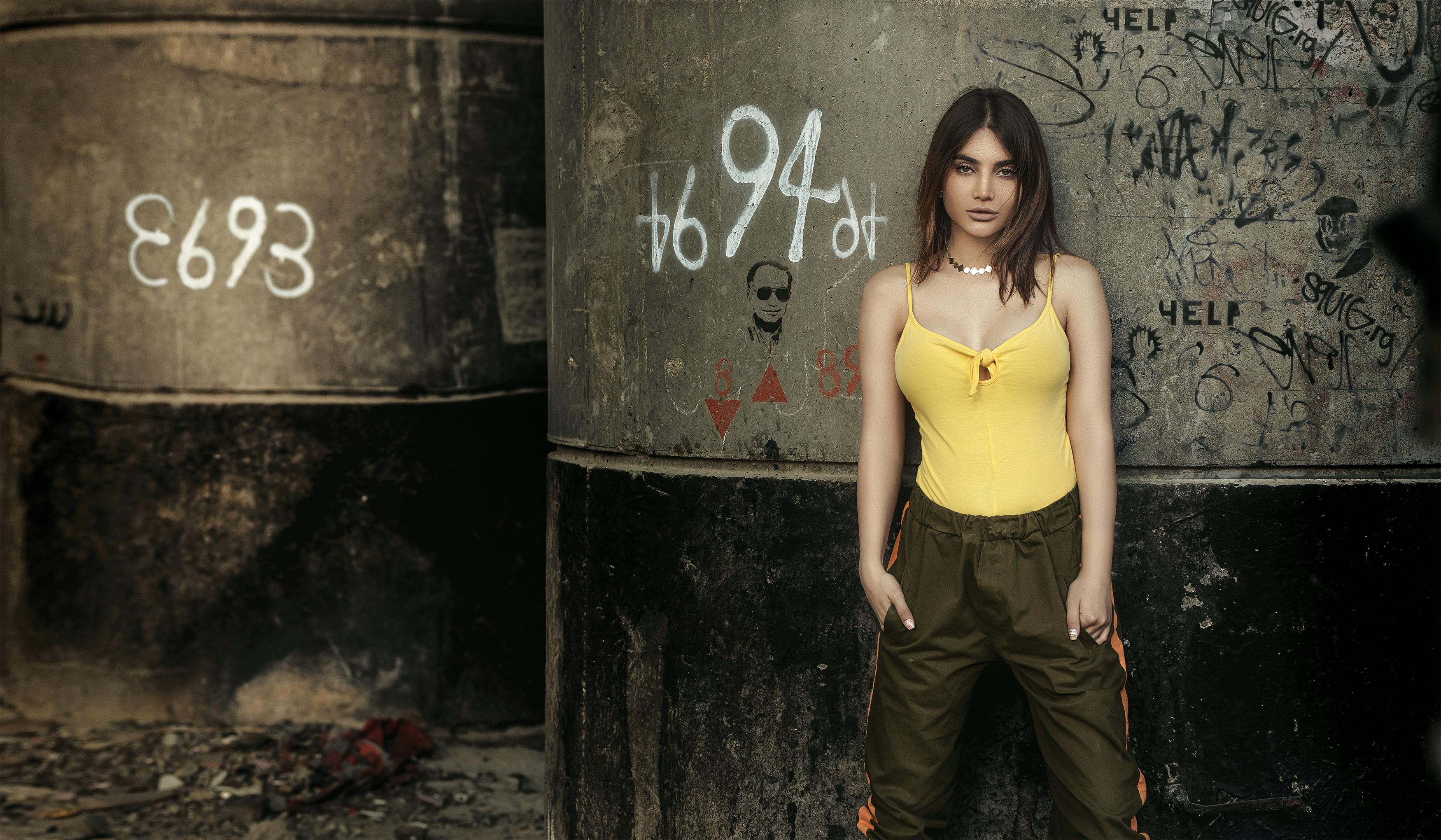 时尚女性在城市环境的涂鸦墙前自信地摆姿势