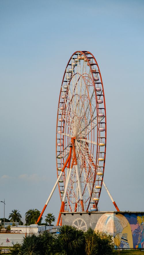 Free Tall red and white ferris wheel at an amusement park set against a clear blue sky. Stock Photo