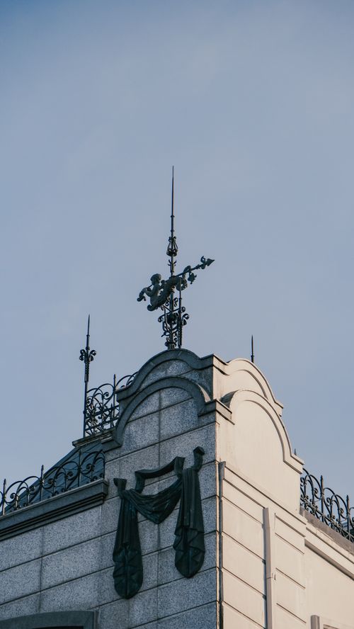 Free An ornate vintage building corner with decorative sculptures under a clear sky, showcasing architectural elegance. Stock Photo