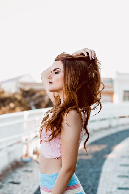 Elegant woman with curly hair posing outdoors, showcasing fashion and beauty.
