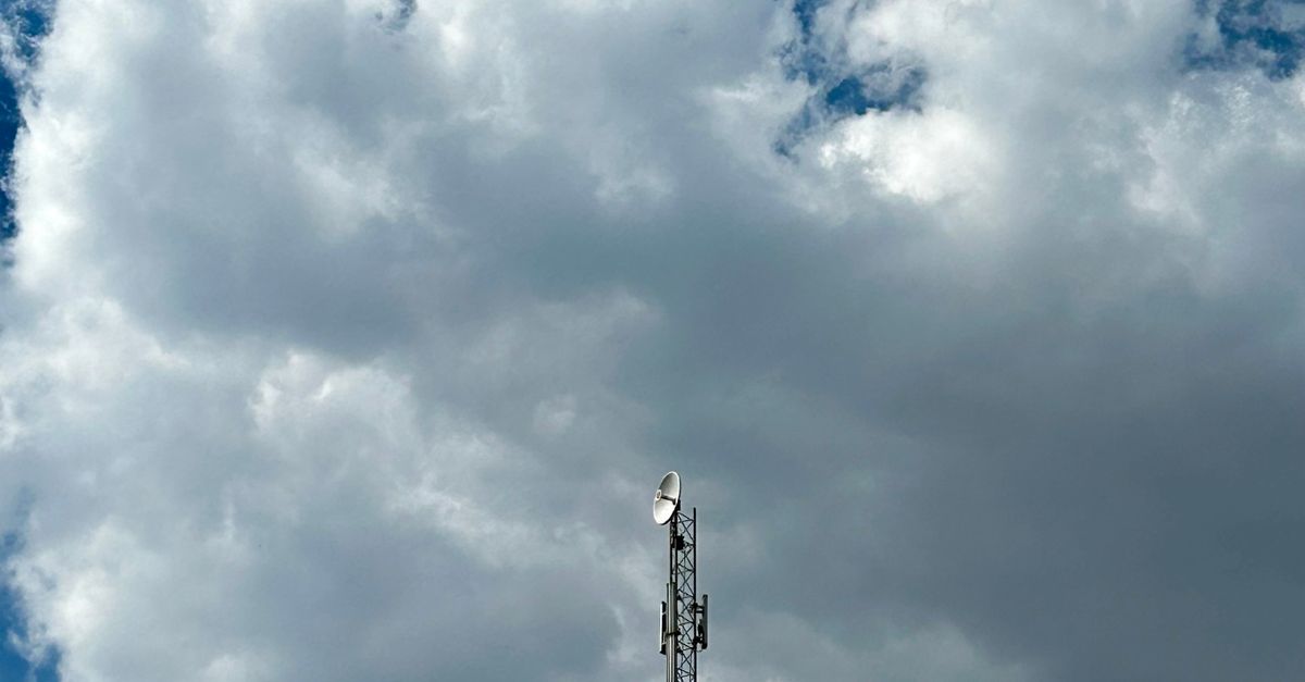 Photo by Abbas A tall transmitter tower reaching into a bright sky with scattered clouds.