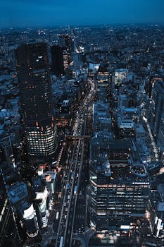 Dramatic aerial view of Tokyo cityscape at night, highlighting skyscrapers and bustling streets.