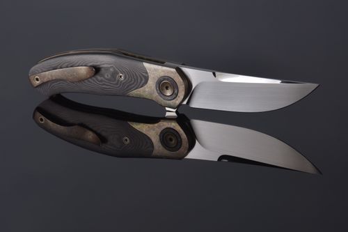 Free High-quality close-up photo of a folding knife with polished metal blade and reflection on gray surface. Stock Photo