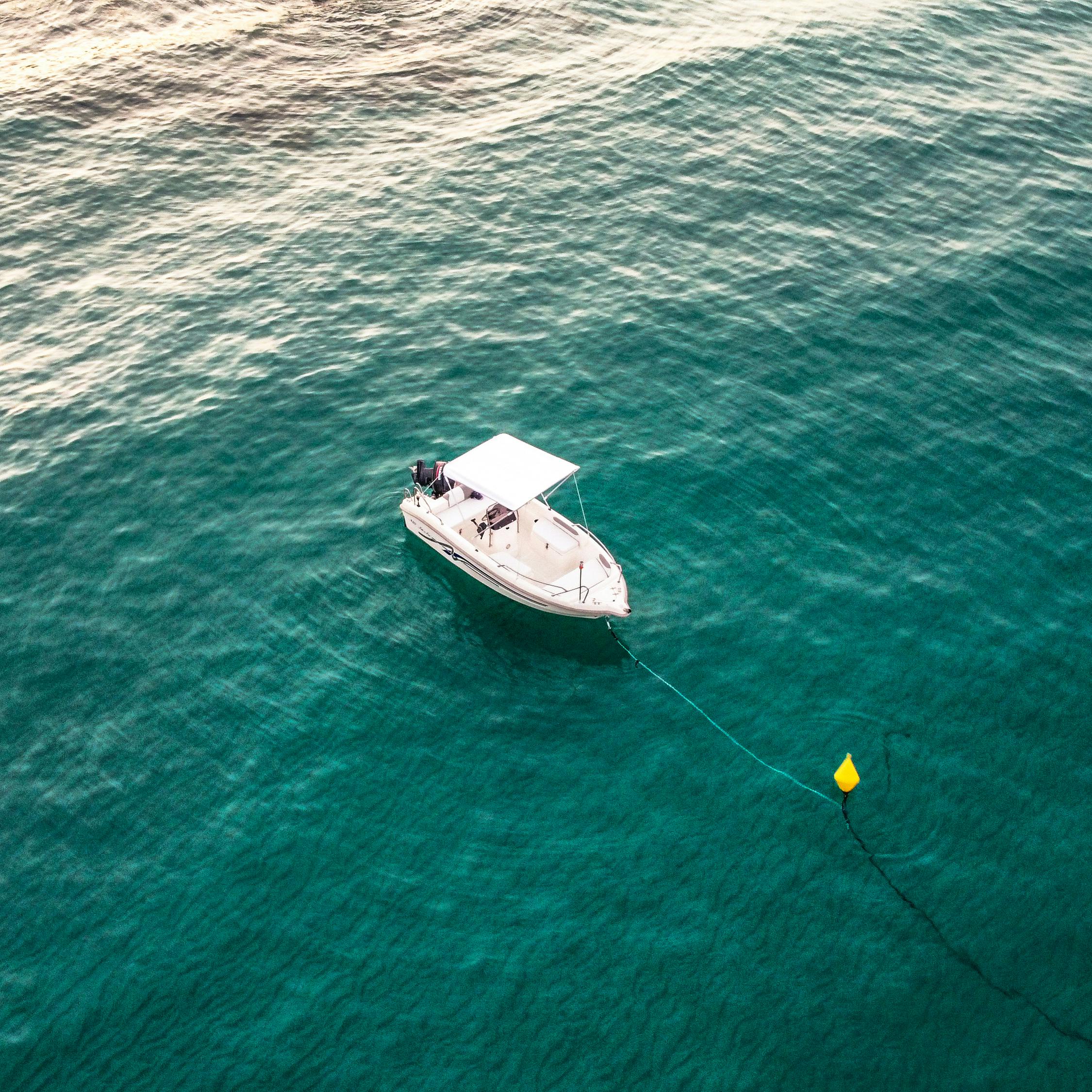 A serene aerial view of a boat moored in clear, turquoise ocean waters, creating a tranquil scene.