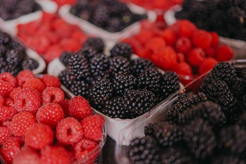 Free A vibrant market display showcasing fresh blackberries and raspberries in containers. Stock Photo