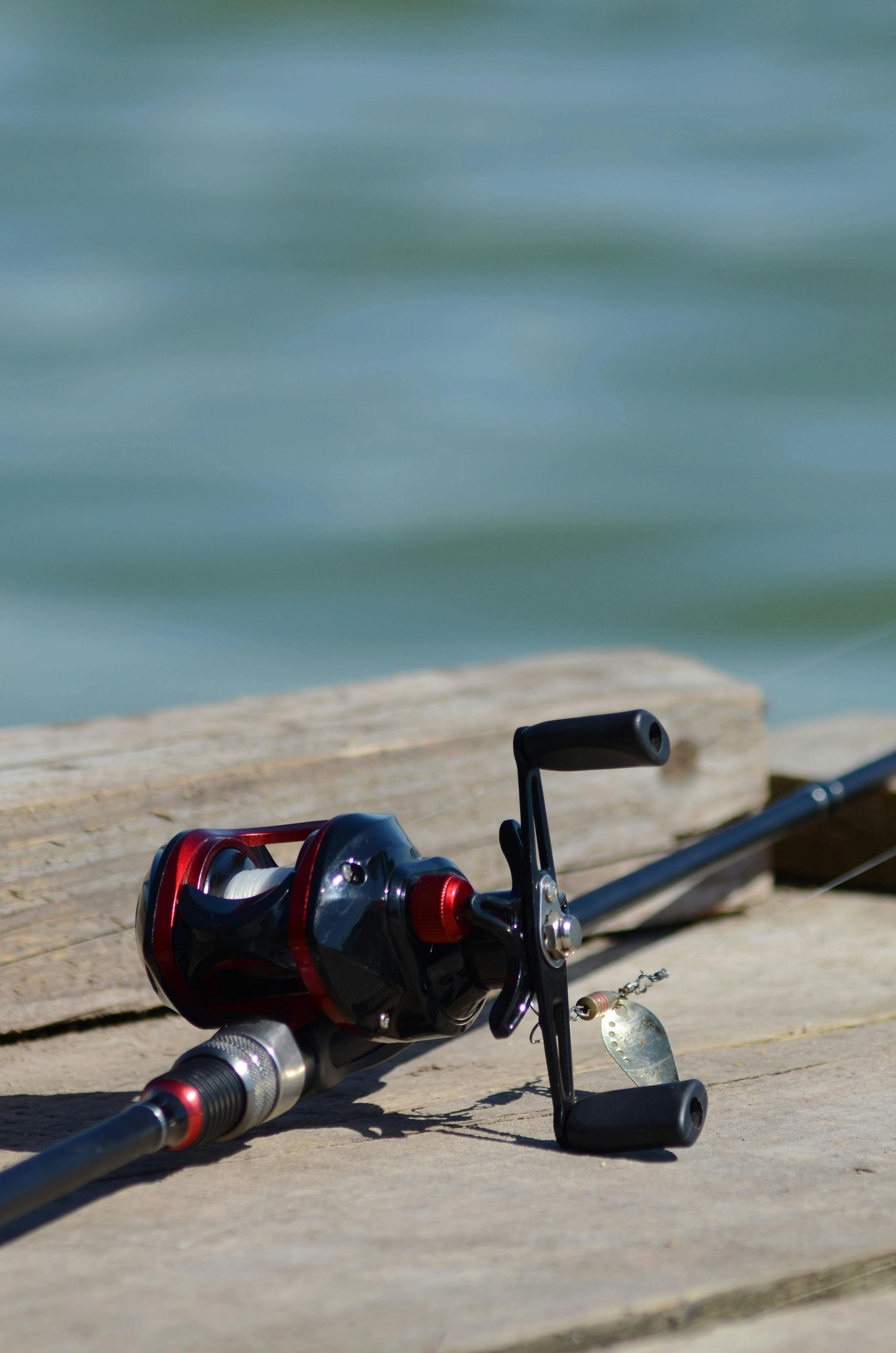 Close-up of a fishing rod laying on a wooden pier by the river.
