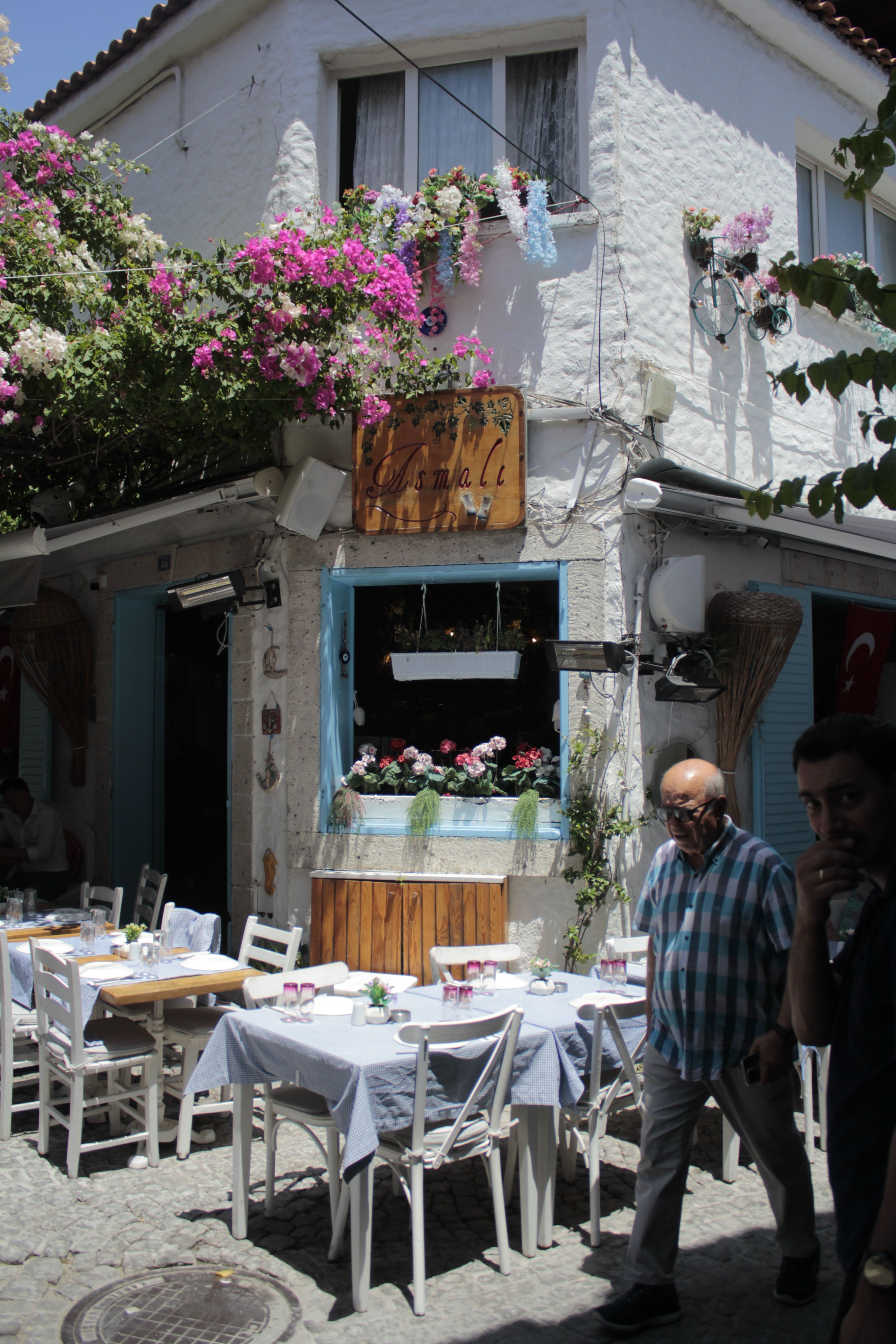 A quaint outdoor café with floral decor on a sunny cobblestone street, perfect for a relaxing day.