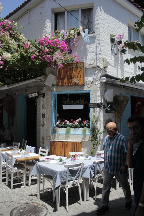 Free A quaint outdoor café with floral decor on a sunny cobblestone street, perfect for a relaxing day. Stock Photo
