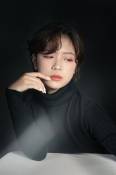 Stylish portrait of a young woman in a black turtleneck, featuring minimalist fashion and neutral tones.