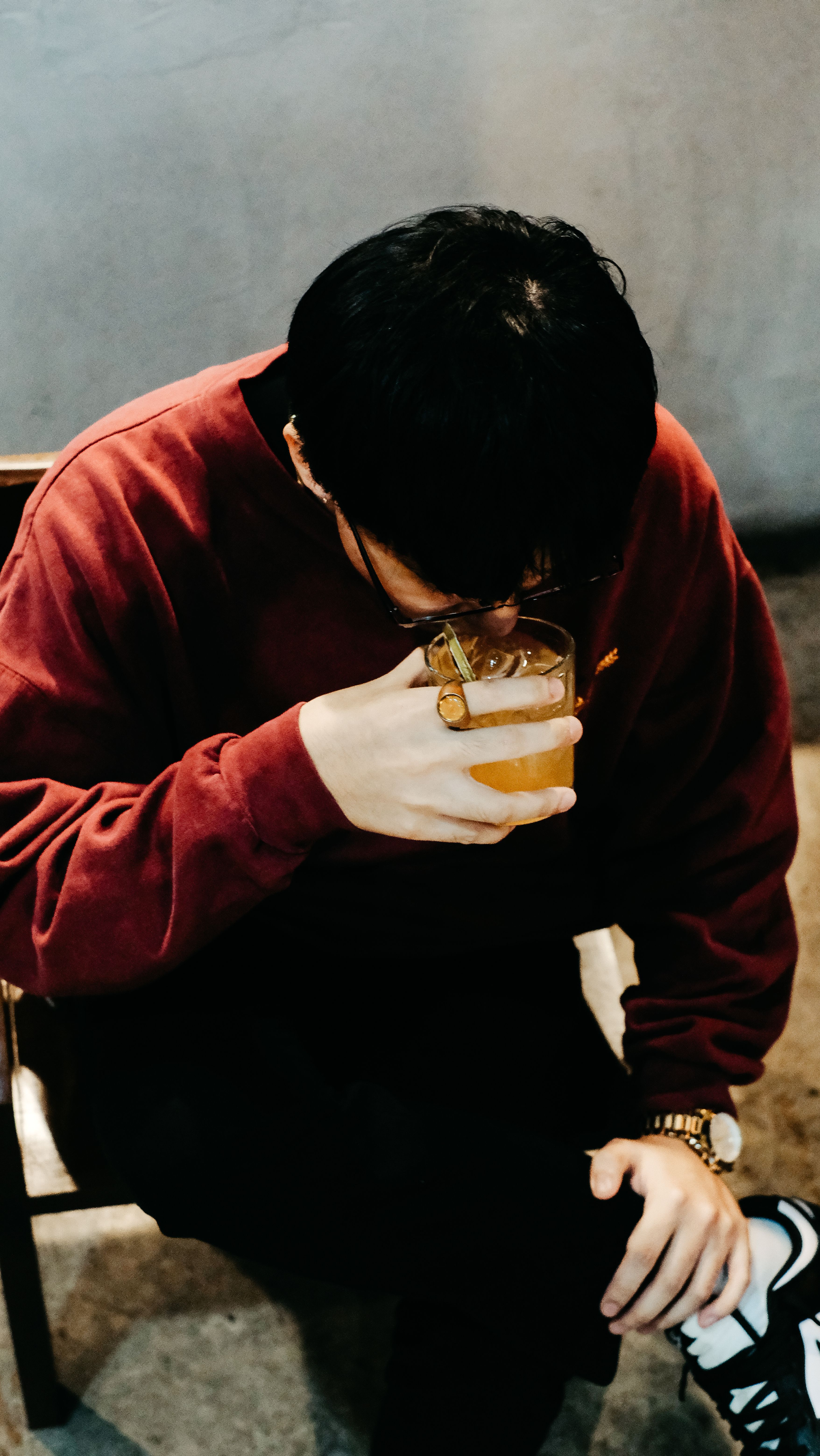A young man in a casual setting enjoys a drink from a glass, captured in an intimate and relaxed moment.