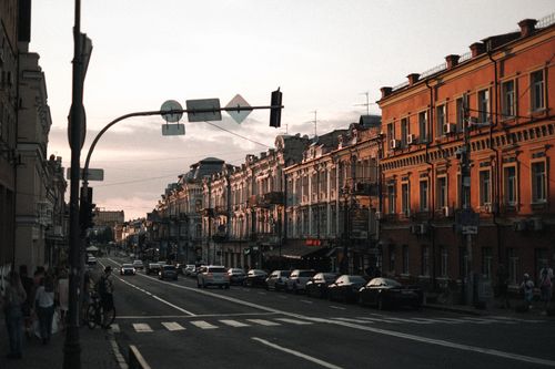 Free View of a classic city street during sunset with historic buildings and light traffic. Stock Photo
