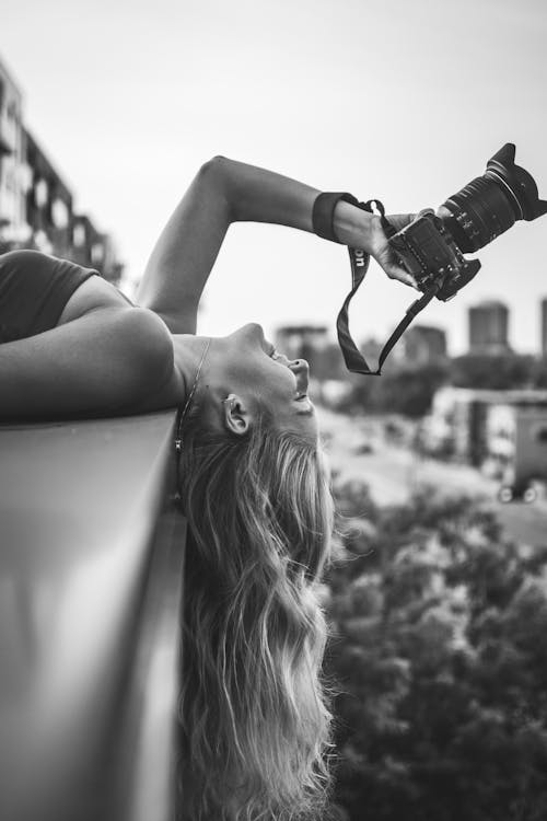 Black and White Photo of a Woman Holding Camera