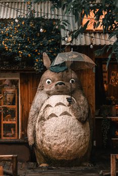 Charming totem sculpture with an umbrella in a rustic outdoor setting, surrounded by foliage.