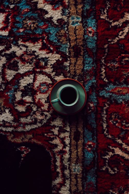 Free Top view of a coffee cup on a vibrant, patterned rug, conveying warmth and comfort. Stock Photo