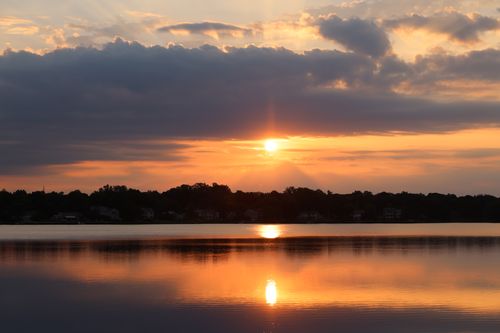 Free A breathtaking sunset reflecting over a tranquil lake, highlighting the serene beauty of nature. Stock Photo