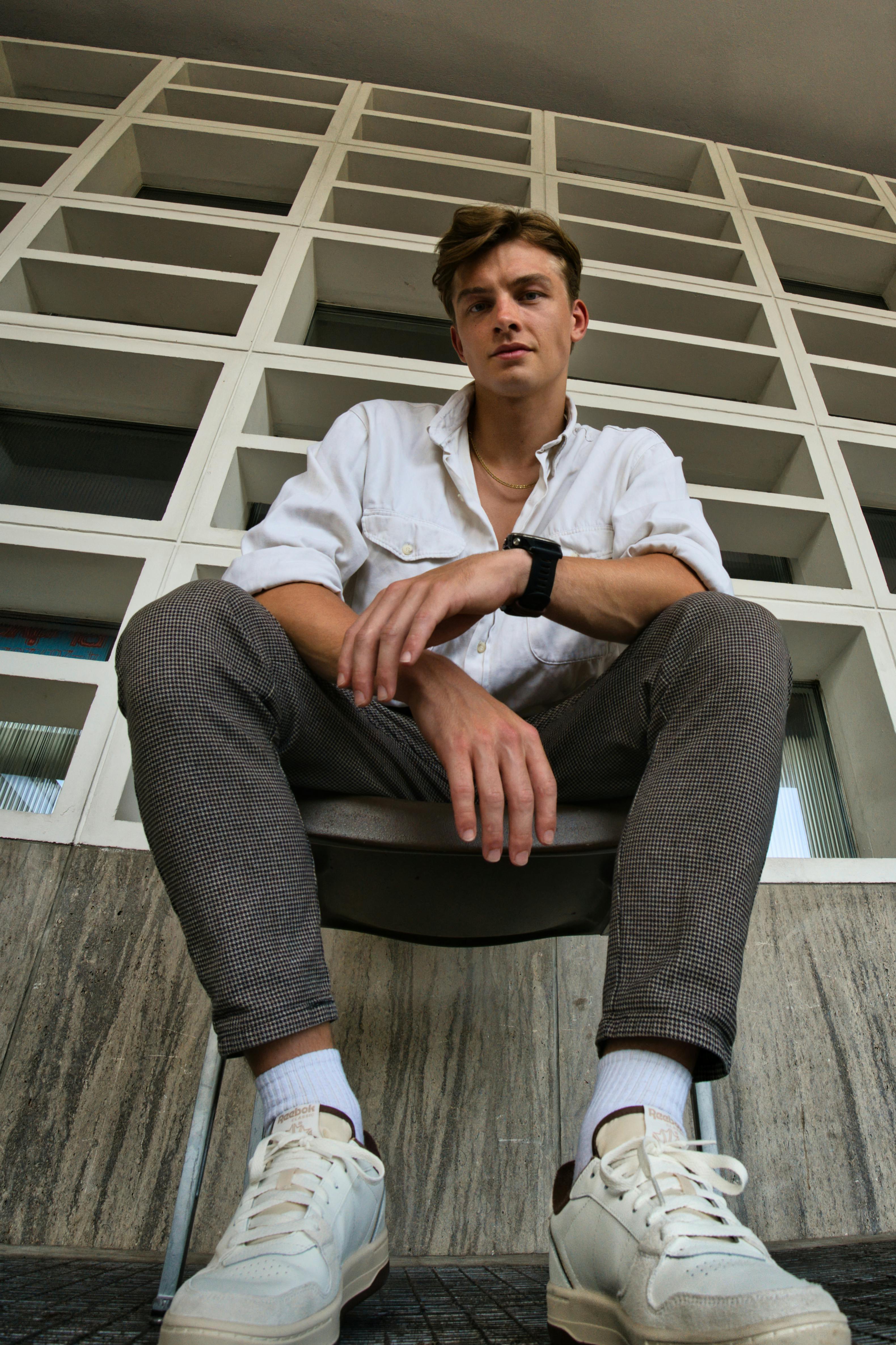 Fashionable young man sitting and posing in a modern urban setting in Berlin.