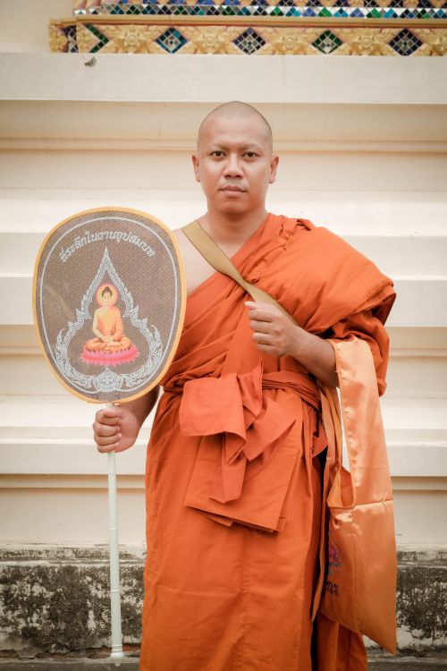 A monk holding a sign with a picture of a buddhist · Free Stock Photo