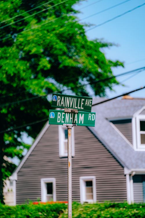 Free Green street sign at the intersection of Rainville Ave and Benham Rd, suburban summer day scene. Stock Photo