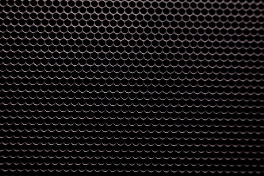 Detailed view of a black metallic grid with small circular holes pattern background.