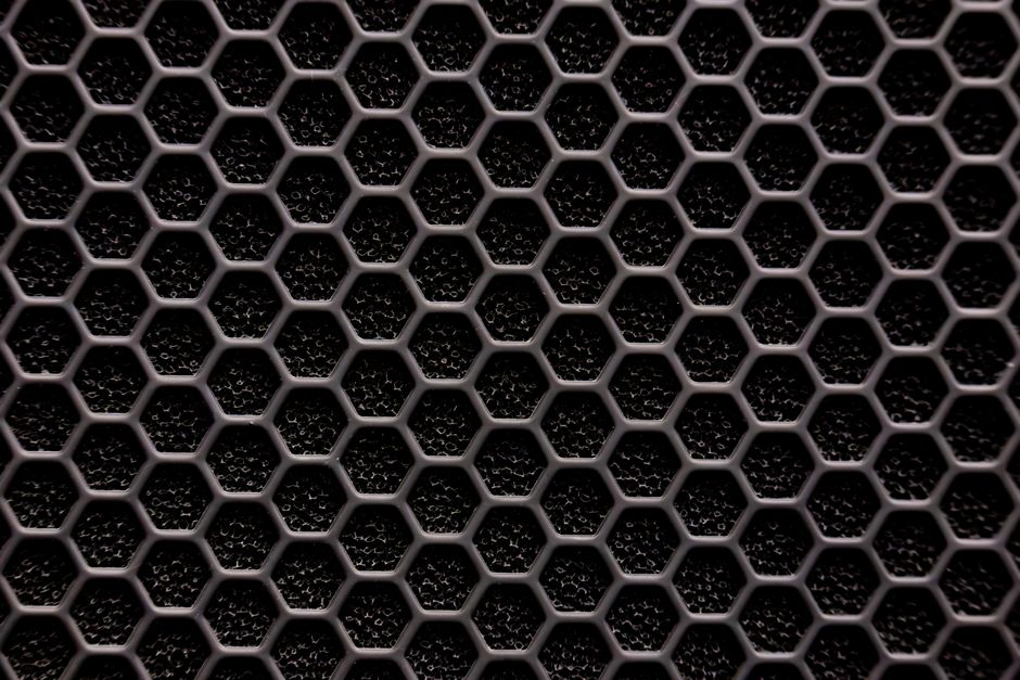 Close-up of a metallic hexagonal grid pattern, resembling a honeycomb structure. Close-up of a metallic hexagonal grid pattern, resembling a honeycomb structure.