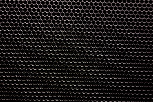 Detailed view of a metallic grille featuring a uniform circular pattern, ideal for industrial design contexts.