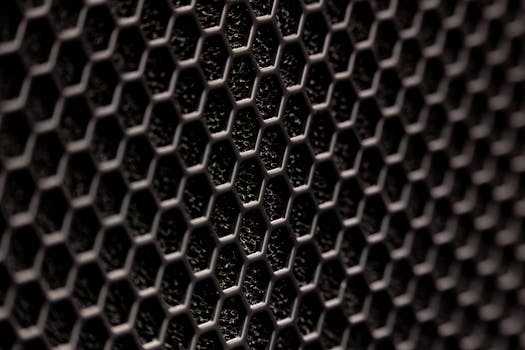 Detailed close-up of a dark hexagonal metal pattern with a textured surface.