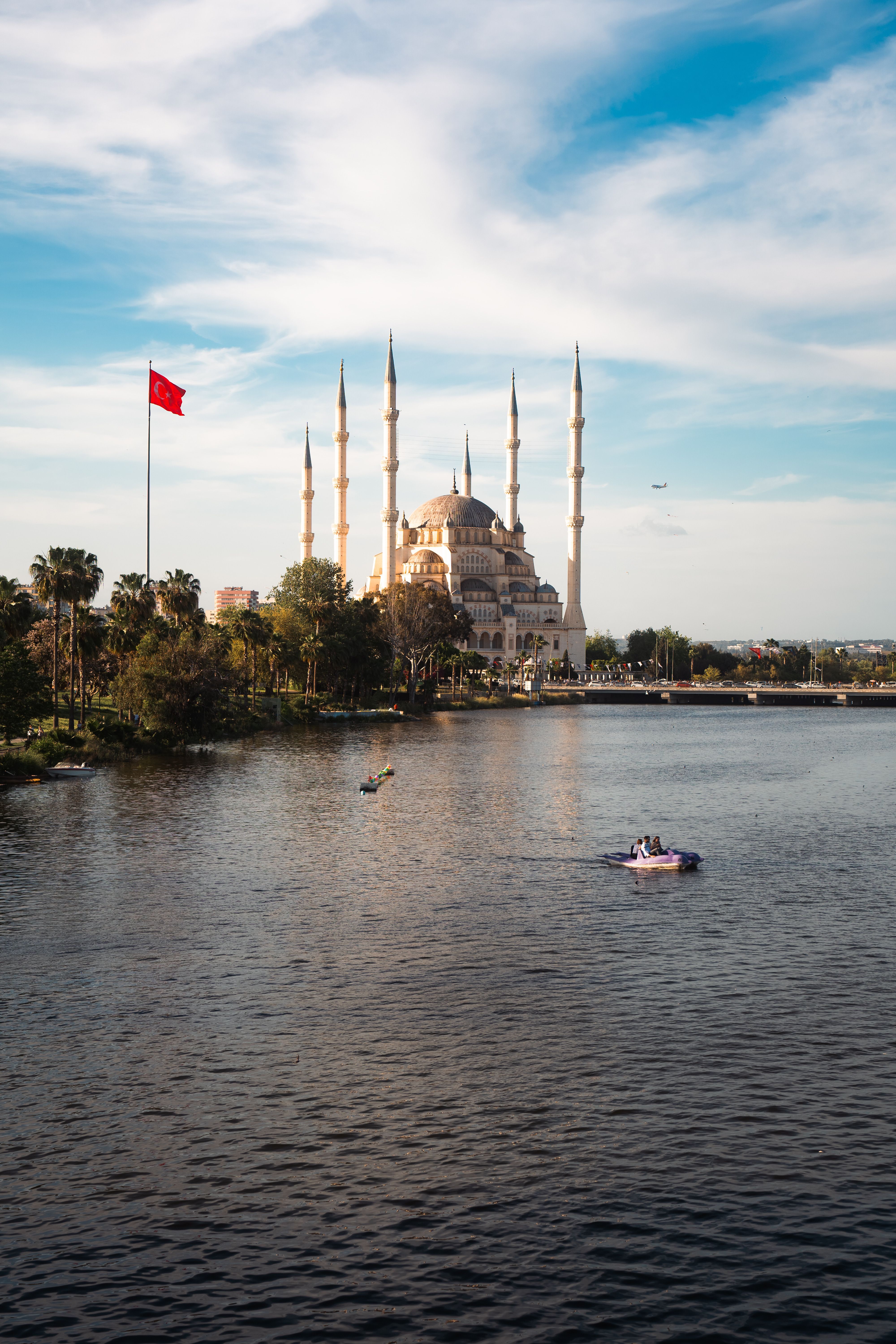 Sabancı Central Mosque with minarets and Turkish flag on a calm river in Turkey.