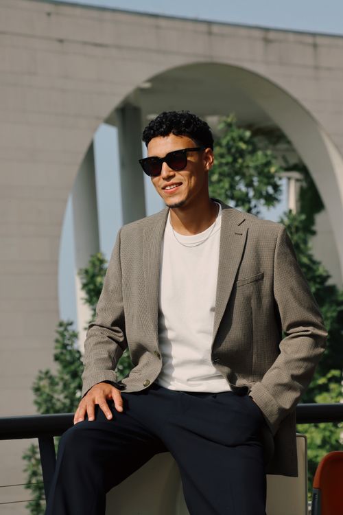 Free Fashionable man in sunglasses and blazer sitting outdoors in Berlin. Urban elegance captured. Stock Photo