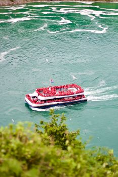 Aerial view of a crowded tourist ferry navigating the stunning turquoise waters of Niagara Falls.