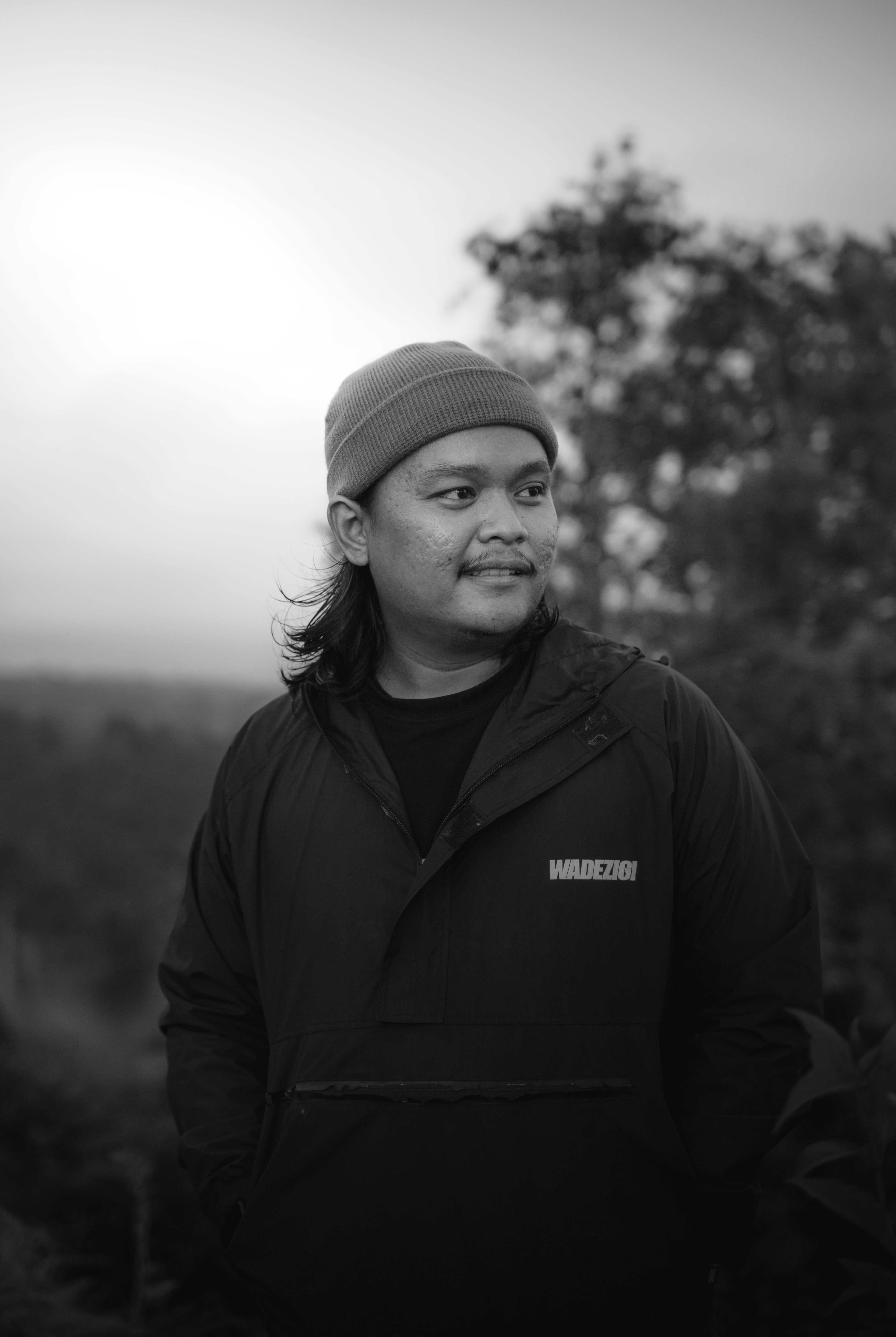 Monochrome portrait of a man in rural setting, wearing a beanie.