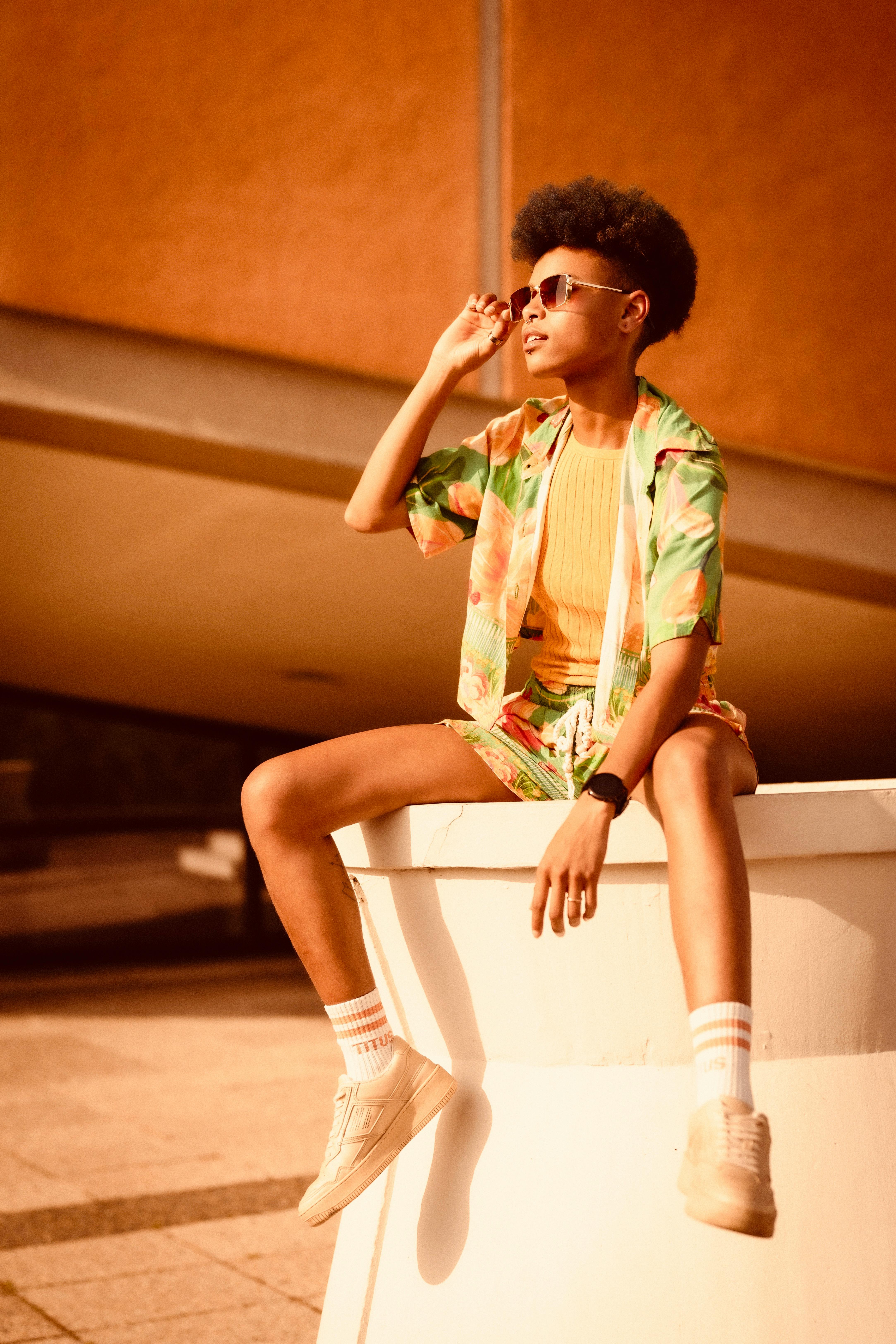 Stylish woman in sunglasses and floral outfit enjoying a sunny urban day.