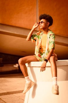 Stylish woman in sunglasses and floral outfit enjoying a sunny urban day.