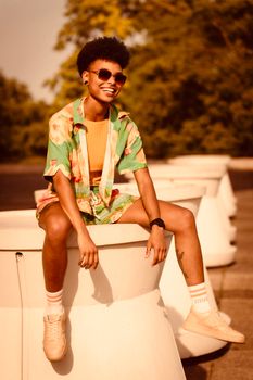 A smiling young adult in vibrant attire enjoys a sunny day in Berlin.