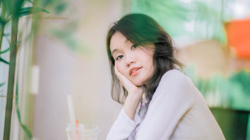 Free Calm indoor portrait capturing a young woman resting her head in her hand with a serene expression. Stock Photo