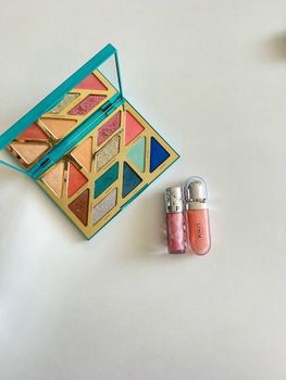 Vibrant makeup palette with lip glosses on a bright background.