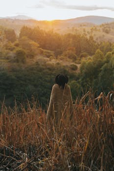 日落时分，一个戴帽子的孤独身影伫立在宁静的秋色里