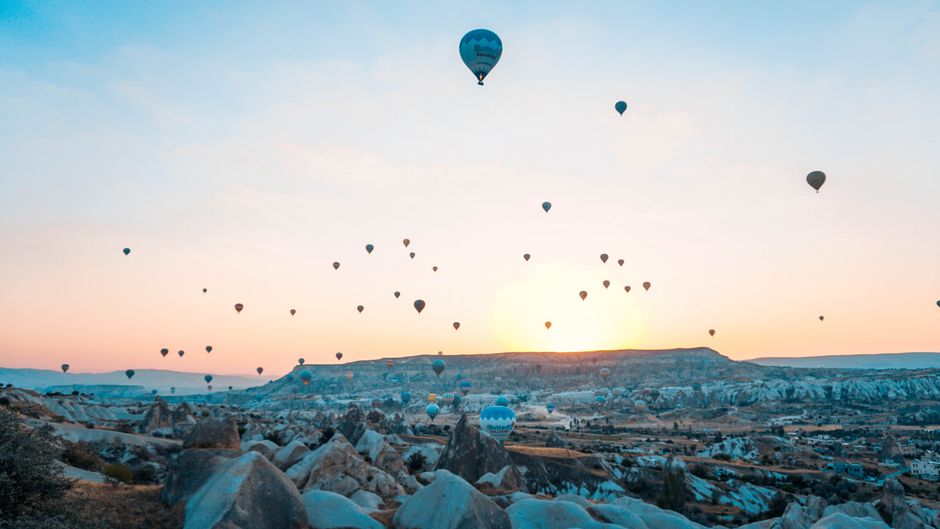 Hot air balloons soar over Cappadocia at sunrise, creating a breathtaking aerial landscape view.
