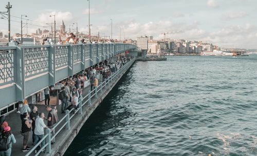 Free Visitors enjoy a sunny day at the bustling Galata Bridge in Istanbul, capturing city life. Stock Photo