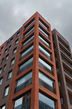 Low angle view of a modern apartment building against a grey sky.