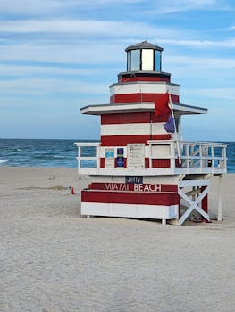 Iconic lifeguard station on Miami Beach with red and white stripes under blue skies.