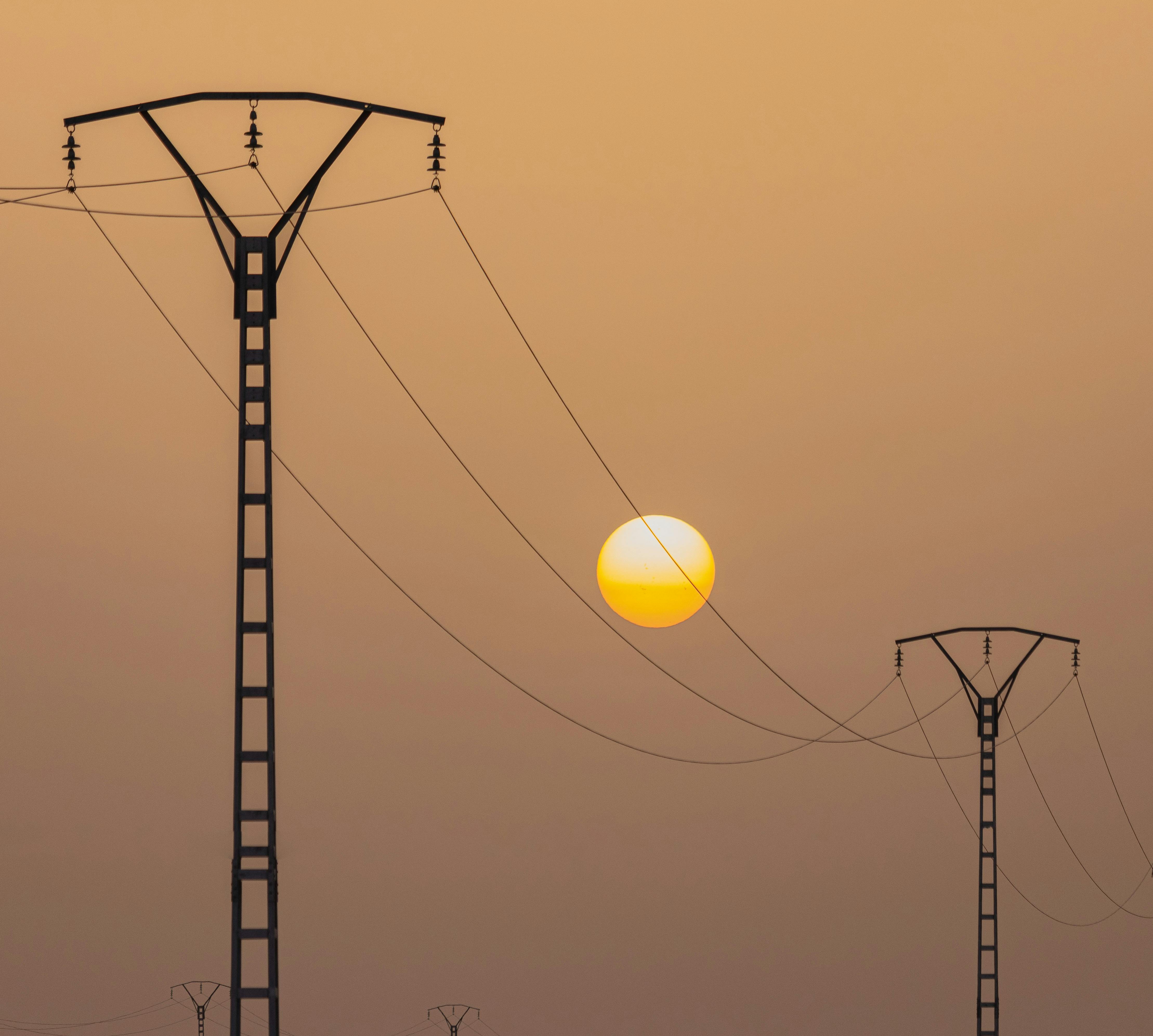 Silhouette of power lines against a vibrant sunset sky in El Menia, Algeria.
