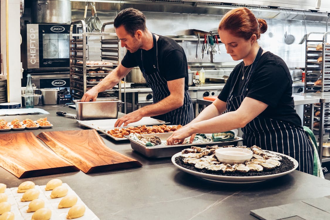 Free Man and Woman Wearing Black and White Striped Aprons Cooking Stock Photo